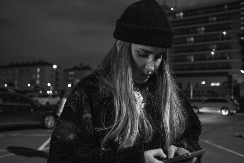 a black and white photo of a woman texting on her phone, by Emma Andijewska, night time footage, wearing beanie, portrait of jossi of blackpink, highresolution
