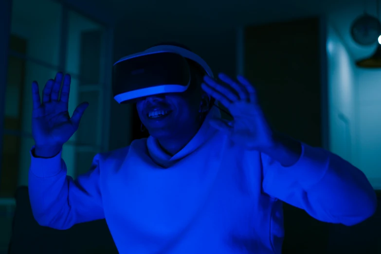 a woman wearing a virtual reality headset in a dark room, a hologram, inspired by Jean Tabaud, pexels contest winner, dramatic white and blue lighting, waving, avatar image, taken with sony alpha 9