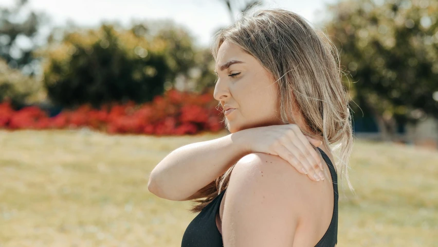 a woman standing in a field with her hand on her shoulder, trending on pexels, swollen muscles, manuka, various posed, neck up