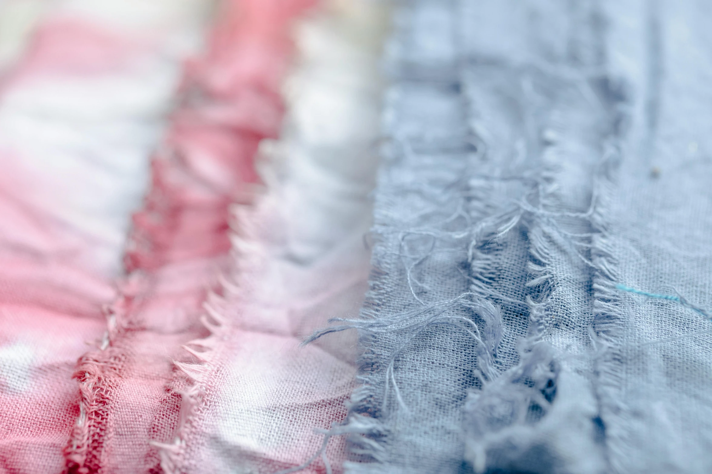 a close up of a piece of fabric on a table, by Sylvia Wishart, unsplash, pink and blue hair, blue and white and red mist, deckle edge, close up shot from the side