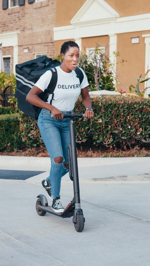 a woman riding an electric scooter down a sidewalk, serena williams, press photo, with a backpack, los angeles ca