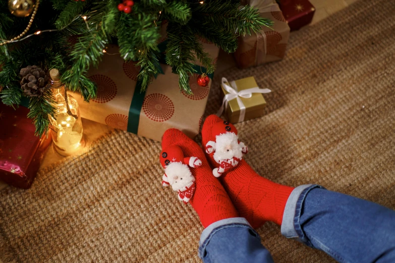 a person wearing red and white socks next to a christmas tree, slippers, with sparkling gems on top, red nose, cosy enchanted scene