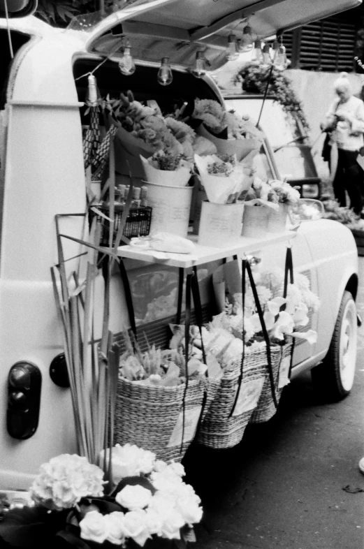 a truck with baskets of flowers on the back of it, a black and white photo, square, food, cars, exhibition