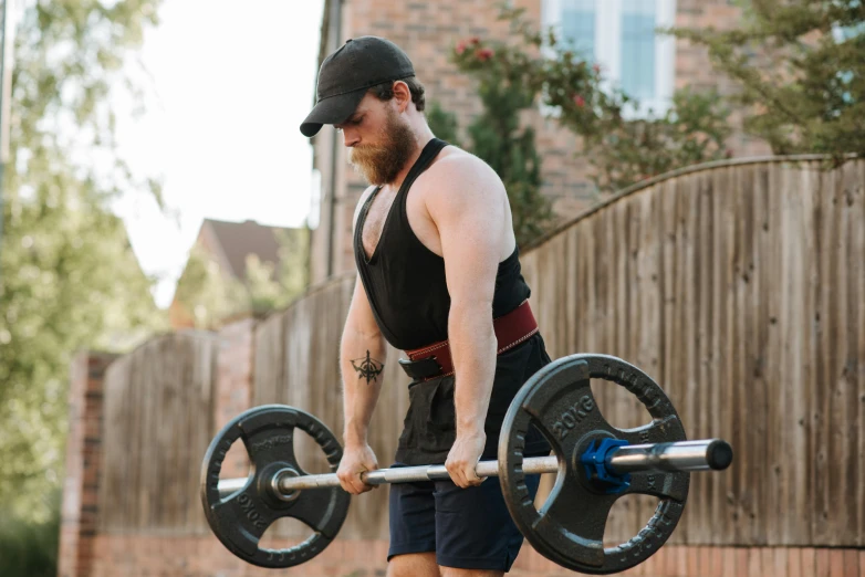 a man with a beard is lifting a barbell, by Joe Bowler, pexels contest winner, carrying two barbells, lachlan bailey, wearing fitness gear, low quality photo