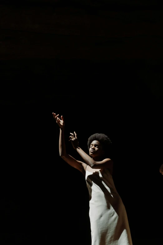 a woman in a white dress standing on a stage, unsplash, black arts movement, black man with afro hair, hands reaching for her, 1974, medium shot of two characters