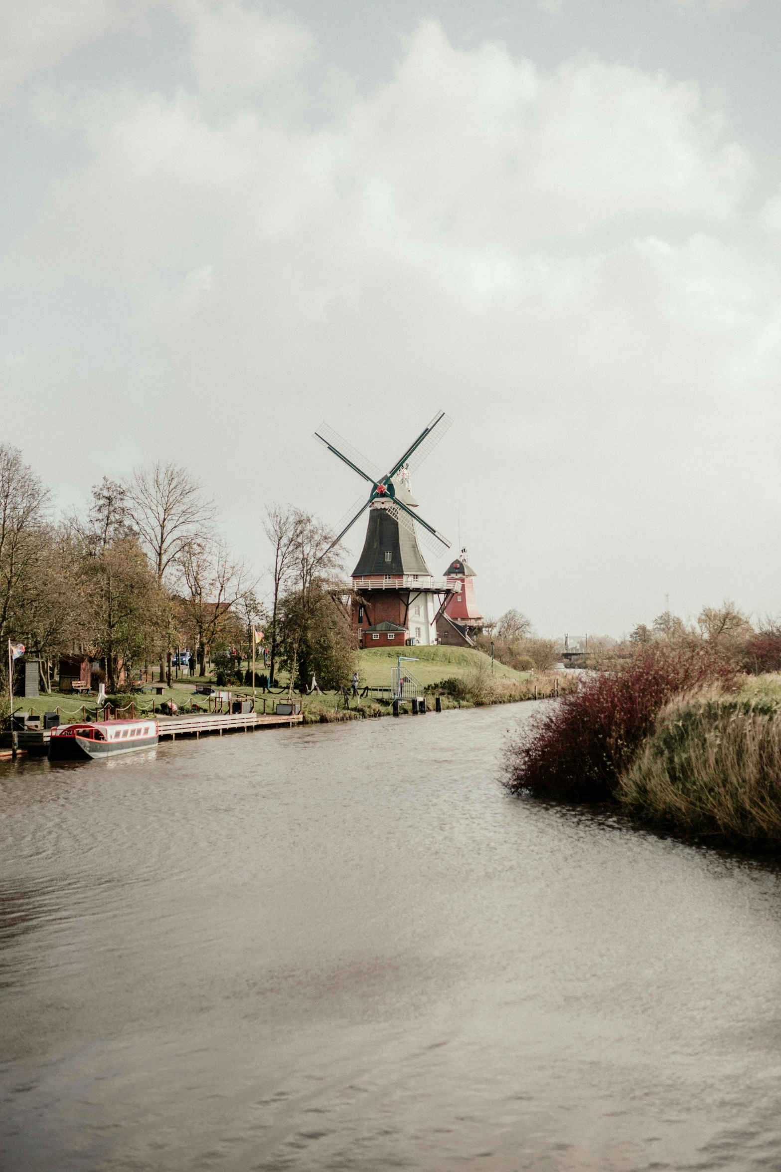 a body of water with a windmill in the background, a picture, pexels contest winner, german romanticism, canals, & a river, low quality photo, color photo