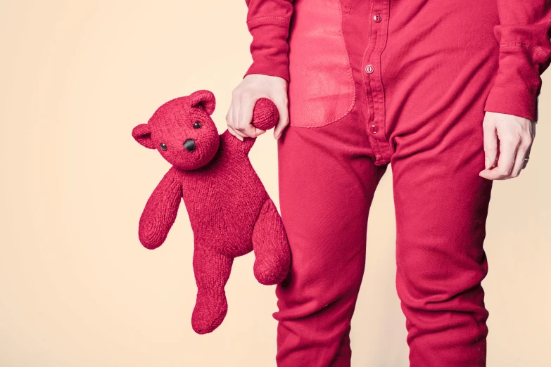 a man in a red shirt holding a red teddy bear, an album cover, inspired by Louise Bourgeois, pexels, red jumpsuit, sleepwear, magenta, closeup - view