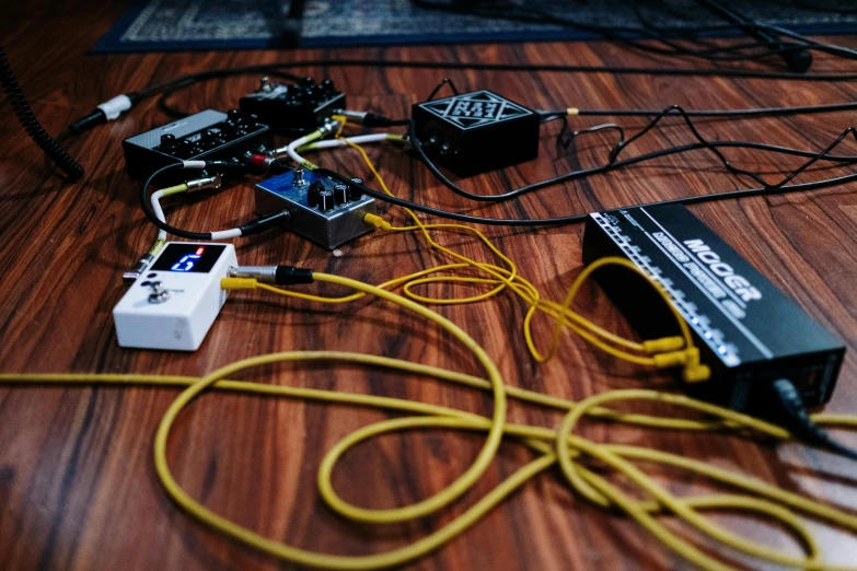 a bunch of electronics sitting on top of a wooden floor, an album cover, by Robbie Trevino, unsplash, cables on floor, instruments, yellow, #screenshotsaturday