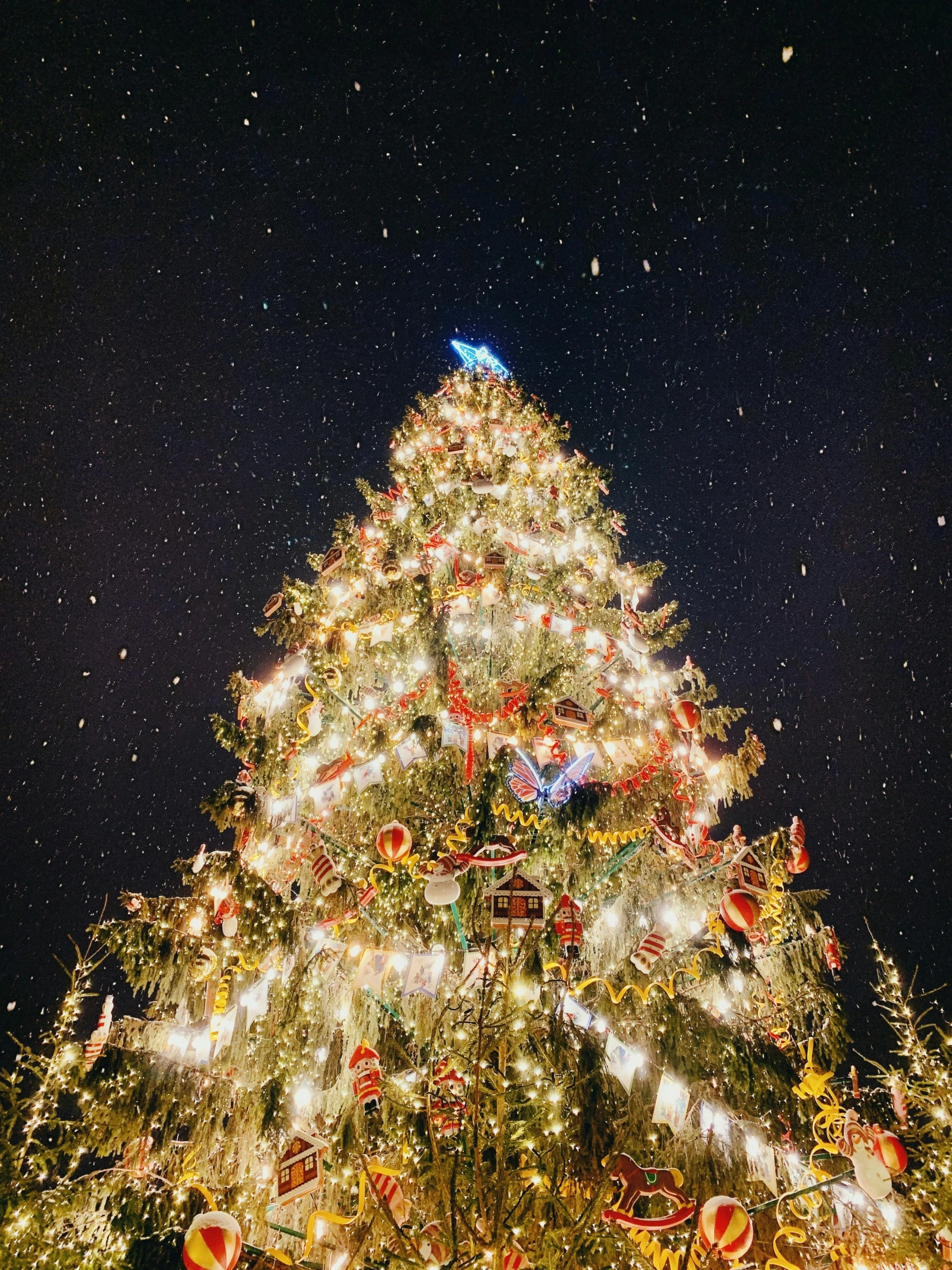 a large christmas tree is lit up at night, by Julia Pishtar, zoomed out to show entire image, thumbnail, high quality image