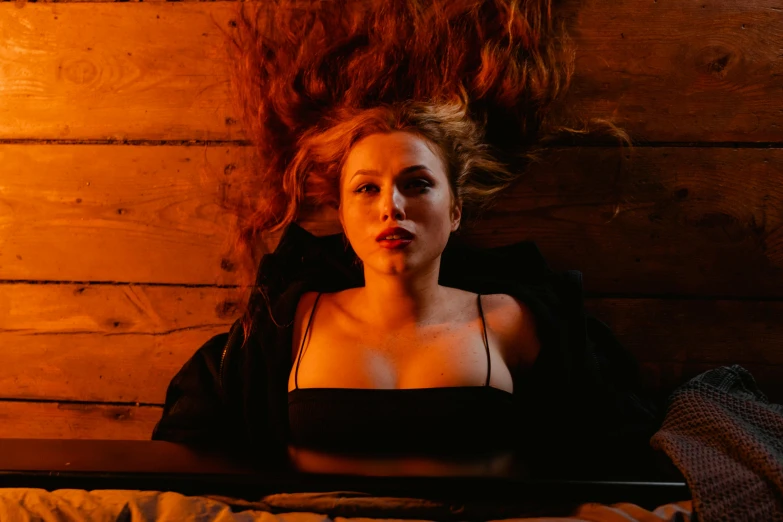 a beautiful young woman laying on top of a bed, an album cover, inspired by Nan Goldin, trending on pexels, renaissance, orange skin and long fiery hair, portrait sophie mudd, in a pitch black room, katheryn winnick