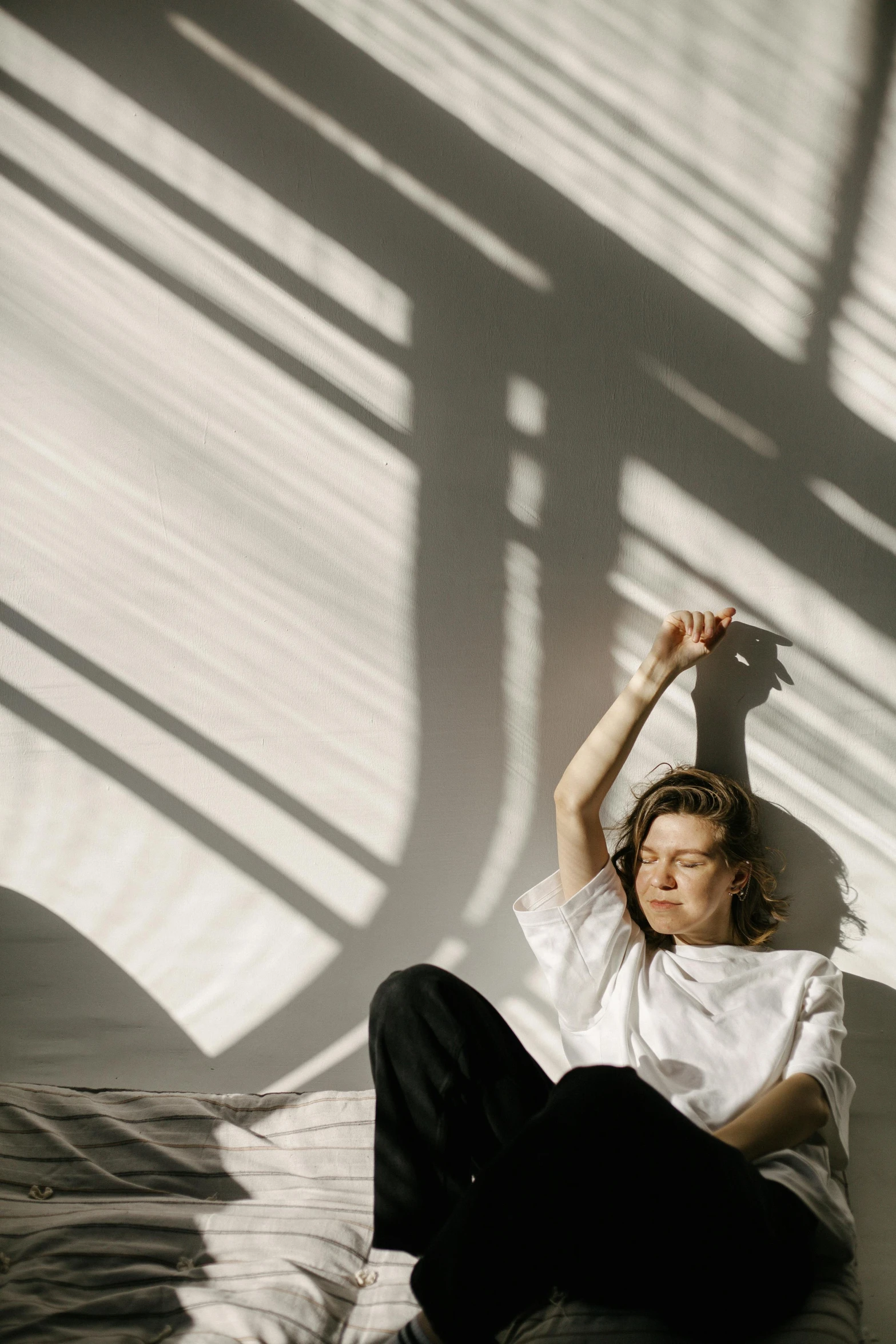 a woman sitting on top of a bed next to a window, trending on pexels, light and space, joe keery, light and shadow effects, androgynous person, sun overhead
