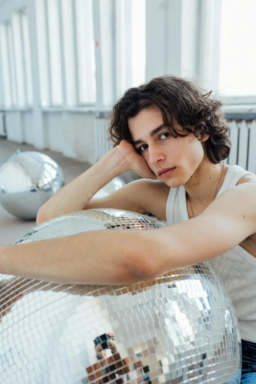 a man sitting on top of a disco ball, androgynous face, with backdrop of natural light, maria panfilova, gen z