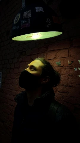 a man standing in front of a brick wall, an album cover, by Adam Marczyński, pexels contest winner, emerging from her lamp, wearing facemask, as she looks up at the ceiling, profile image