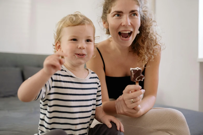 a woman and a child sitting on a bed, pexels contest winner, happening, eating ice - cream, avatar image, excited, rocky roads