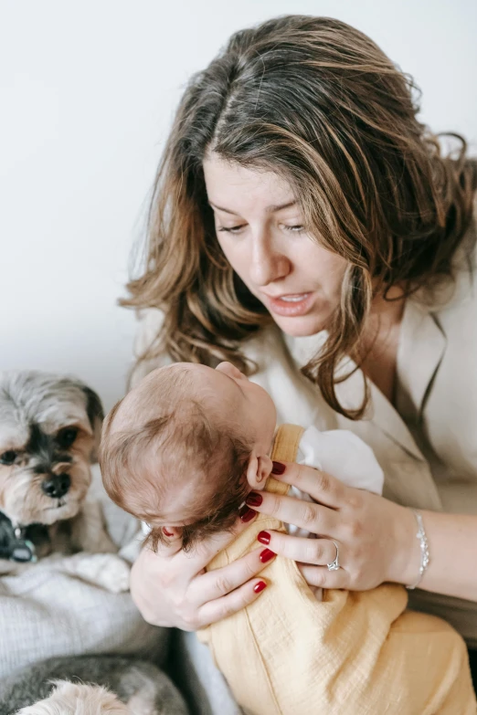 a woman holding a baby next to a dog, trending on pexels, concerned expression, bedhead, grieving, detail shot