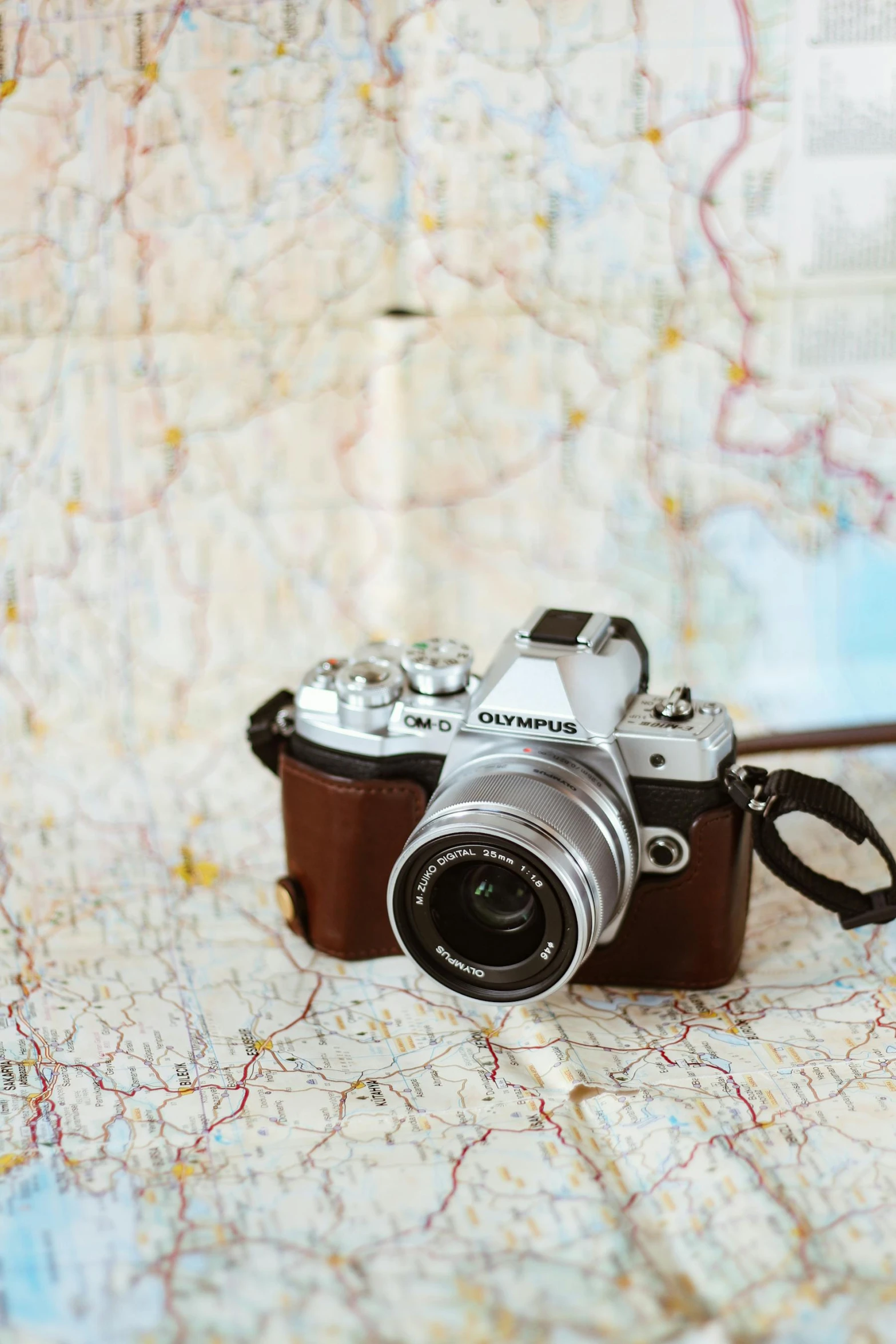 a camera sitting on top of a map, olympus, tan, grey, brown