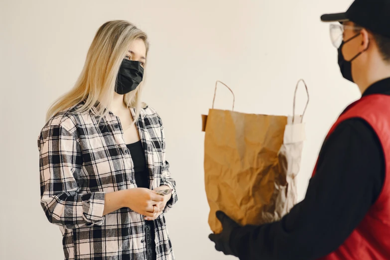 a man in a face mask is handing a paper bag to a woman, pexels contest winner, black bandana mask, alana fletcher, looking partly to the left, hot food