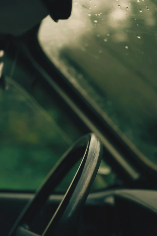 a close up of a steering wheel in a car, a picture, inspired by Elsa Bleda, unsplash, tonalism, green hood, window ( rain ), looking left, faded