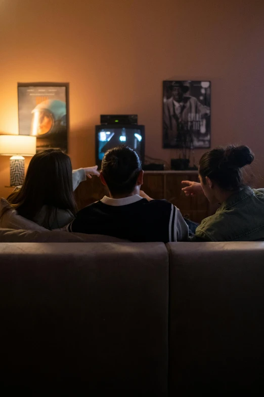 a group of people sitting on a couch watching tv, inspired by Nan Goldin, pexels, soft lighting 8k, ignant, gaming room, ( ( theatrical ) )