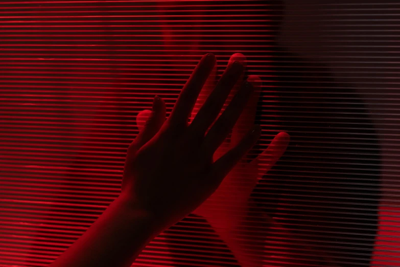a person standing in front of a red light, an album cover, inspired by Elsa Bleda, pexels contest winner, interactive art, close-up of thin soft hand, red lasers, soft light through blinds, red monochrome