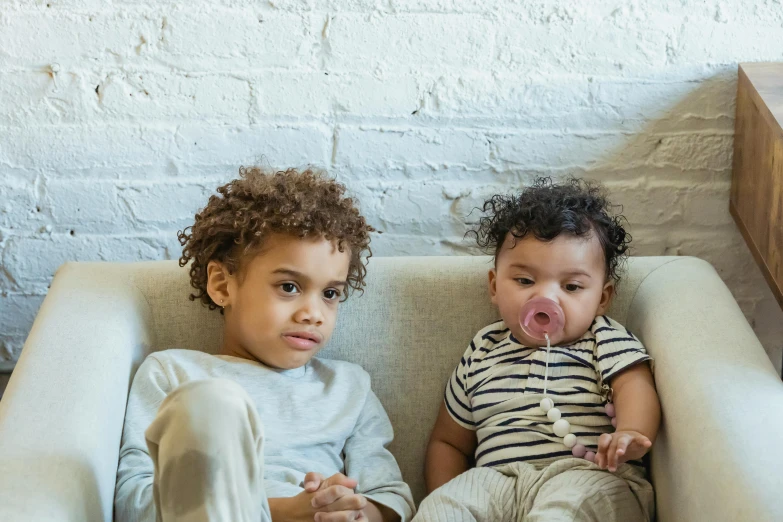 a couple of kids sitting on top of a couch, by Nina Hamnett, pexels contest winner, with brown skin, soft lulling tongue, third trimester, two male
