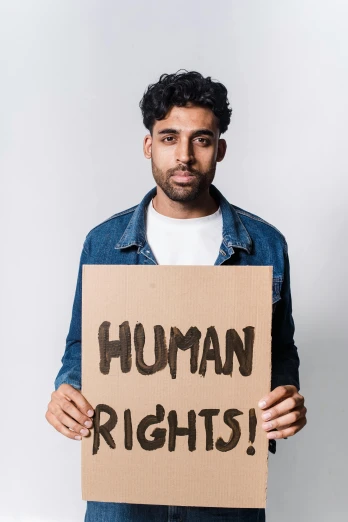 a man holding a sign that says human rights, an album cover, by Arabella Rankin, shutterstock, renaissance, indian, looking straight, thumbnail, profile pic