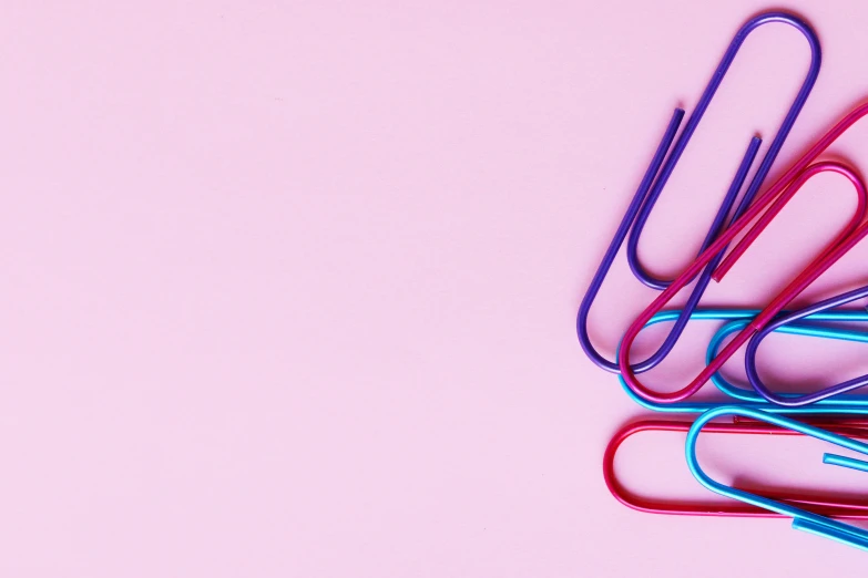 a bunch of paper clips sitting on top of a pink surface, trending on pexels, brand colours are red and blue, curves, purple tubes, josh grover