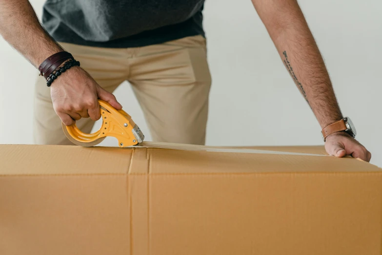 a man holding a stapler on top of a cardboard box, by Carey Morris, pexels contest winner, hurufiyya, avatar image, full pallet image, decoration, half body photo