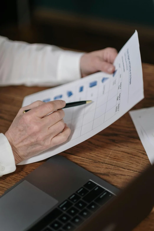 a person sitting at a table with papers and a laptop