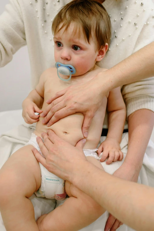 a woman putting a pacifier on a baby's diaper, a picture, local conspirologist, thumbnail, portrait image