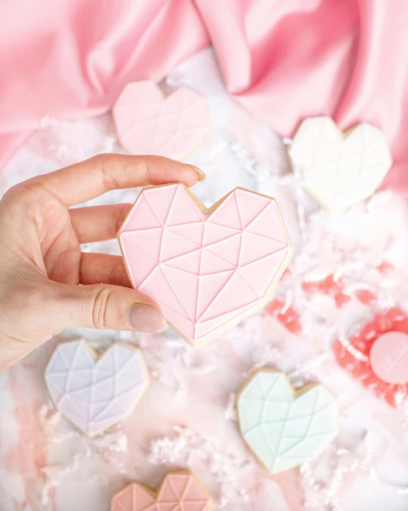 a close up of a person holding a heart shaped cookie, featured on instagram, crystal cubism, modern pastel colours, embossed, wedding, faceted