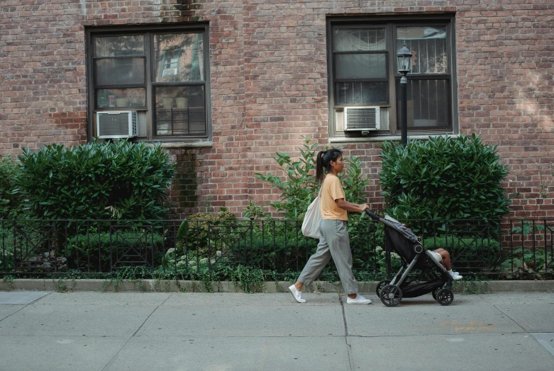 a woman walking down a sidewalk with a stroller, by Carey Morris, pexels contest winner, lush brooklyn urban landscaping, alexandria ocasio cortez, an olive skinned, ignant