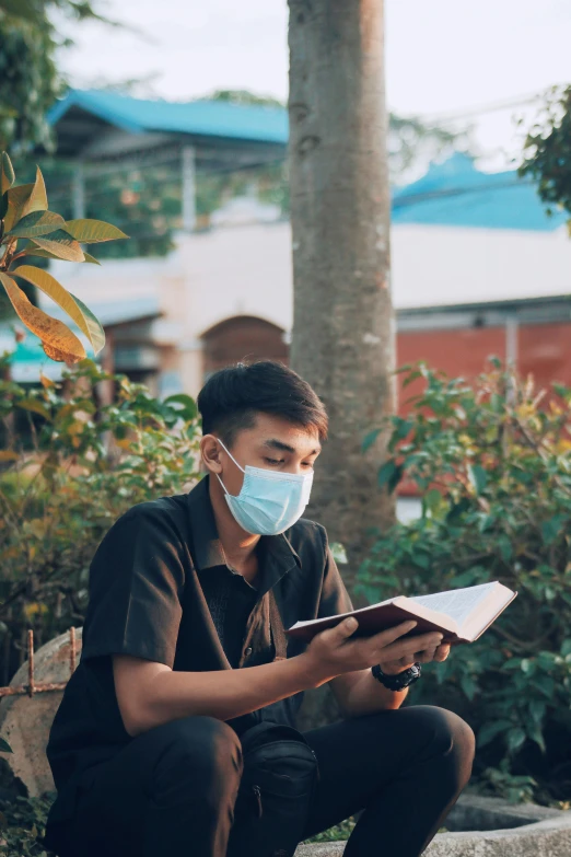 a man wearing a face mask reading a book, happening, jc park, darren quach, modest, medicine