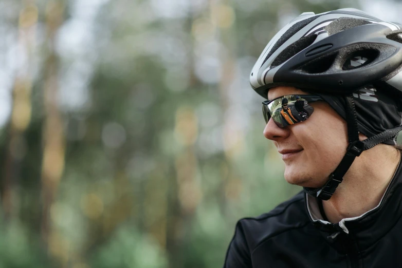 a close up of a person wearing a helmet and sunglasses, by Jaakko Mattila, sport glasses, forrest in background, lifestyle, black