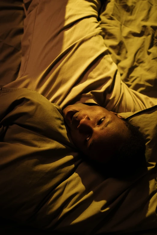 a man laying on top of a bed under a blanket, happening, jordan peele's face, serious lighting, ( ( theatrical ) ), promo image
