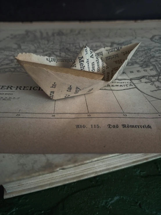 a paper boat sitting on top of a map, by Jessie Algie, set in ww2 germany, photography ultrafine detail, small, made of cardboard