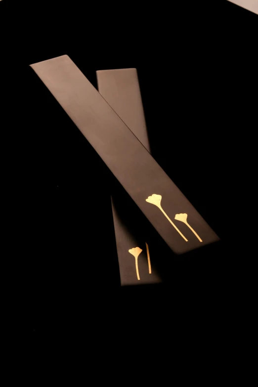 a pair of scissors sitting on top of a table, inspired by Inshō Dōmoto, hurufiyya, golden embers flying, on black background, sleek spines, lotus
