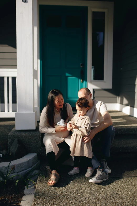 a man and woman sitting on the steps of a house, by Maggie Hamilton, pexels contest winner, portrait of family of three, lulu chen, seattle, blue door