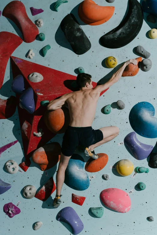 a man standing on top of a climbing wall, trending on pexels, process art, slightly muscular, promo image, boulders, indoor picture