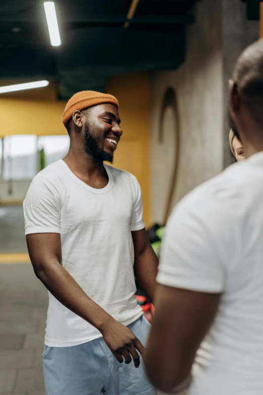 a couple of men standing next to each other, trending on pexels, happening, local gym, smiling at each other, african man, wearing white clothes