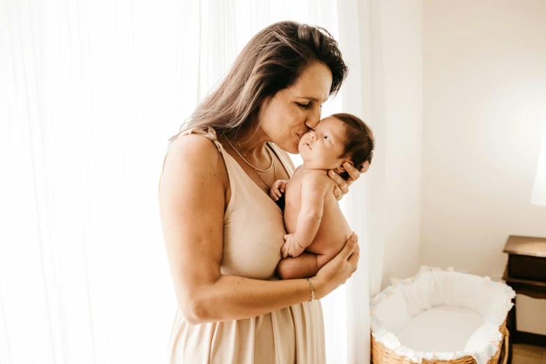 a woman holding a baby in her arms, a photo, by Carey Morris, pexels contest winner, beige, avatar image, brunette, thumbnail