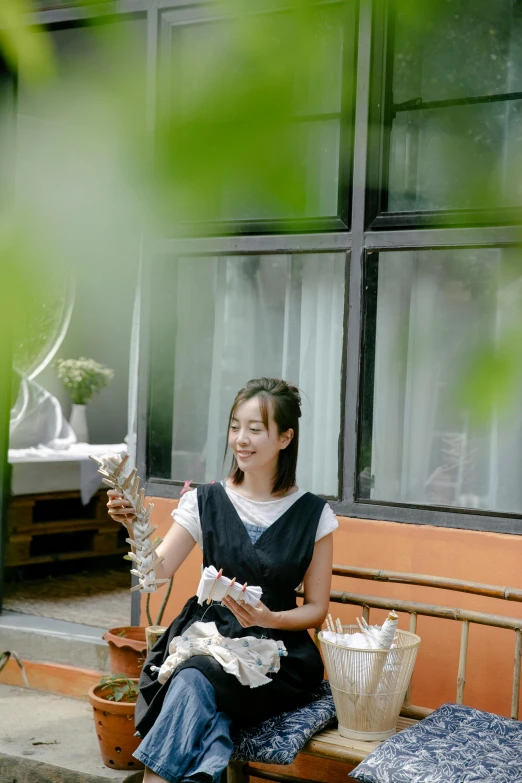 a woman sitting on a bench in front of a building, in the garden, phong shaded, ( waitress ) girl, profile pic