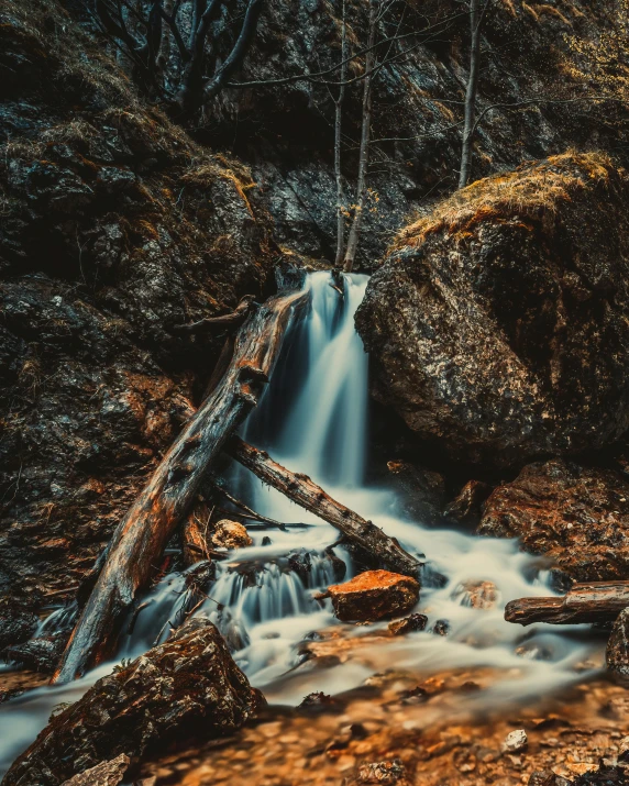 a small waterfall in the middle of a forest, a picture, unsplash contest winner, 8k detail post processing, brown water, rugged, set photo