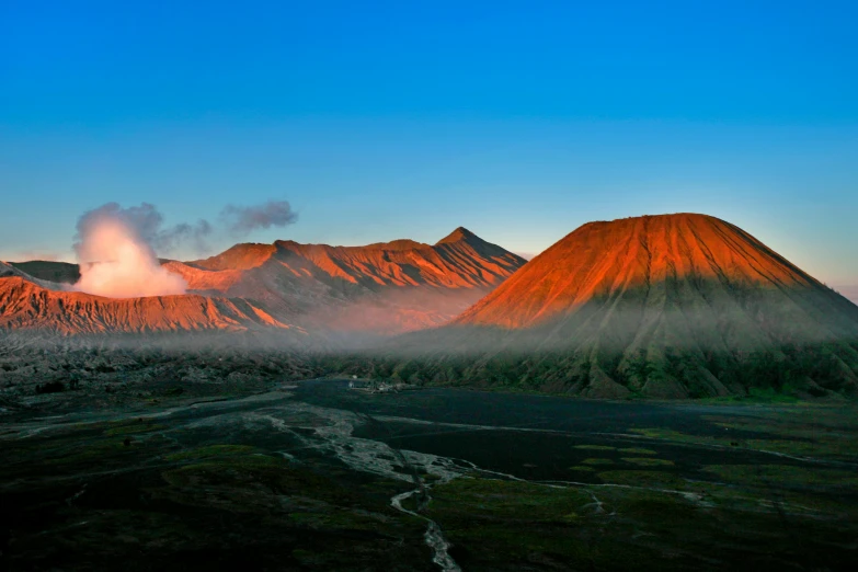 a mountain that has a lot of smoke coming out of it, a matte painting, by Julia Pishtar, pexels contest winner, sumatraism, iceland hills in the background, morning glow, frans lanting, panoramic