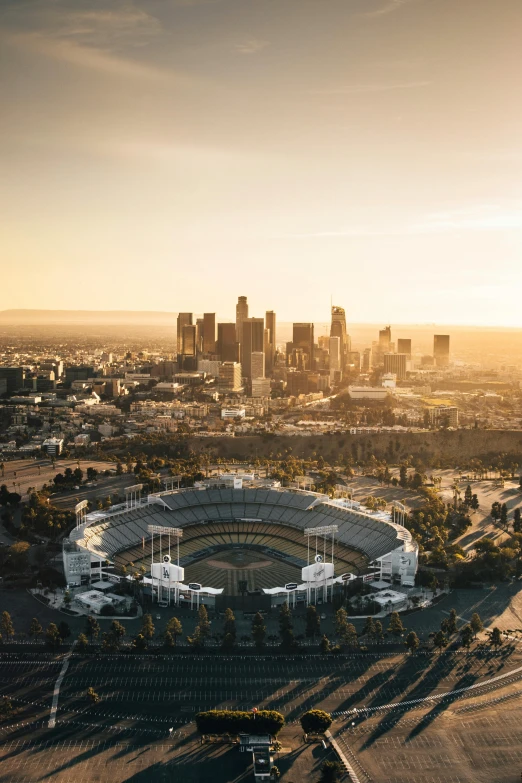 an aerial view of a baseball stadium with a city in the background, by Brad Holland, unsplash contest winner, los angelos, golden morning light, promo image, multiple stories