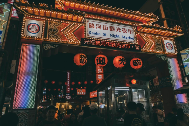 a group of people standing in front of a building, a picture, neon signs, chinese lanterns, busy night, tastes