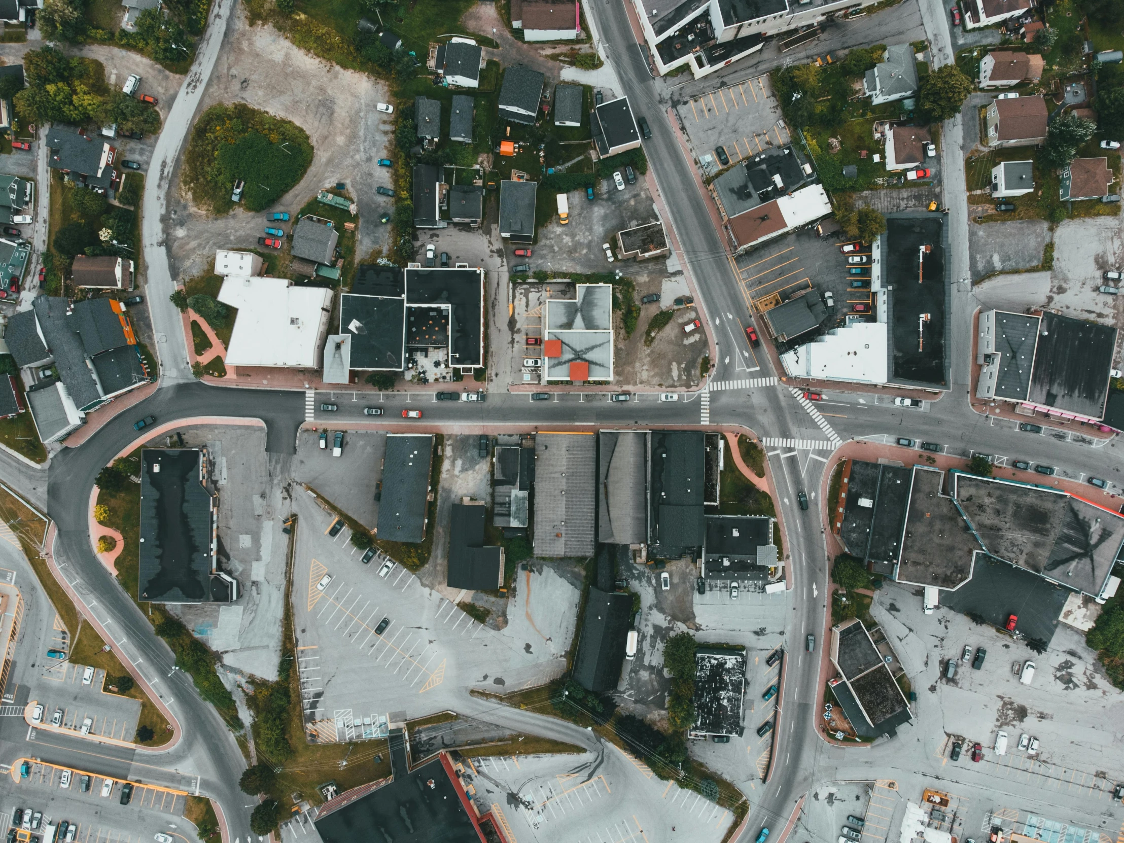 an aerial view of a city with lots of buildings, by Jaakko Mattila, unsplash, photorealism, intersection, grey, brown