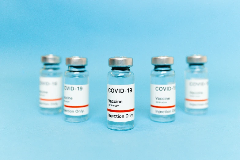 three vials of covidd - 19 vaccine on a blue background, a picture, by Gavin Hamilton, shutterstock, 6 pack, colour corrected, label, on a gray background