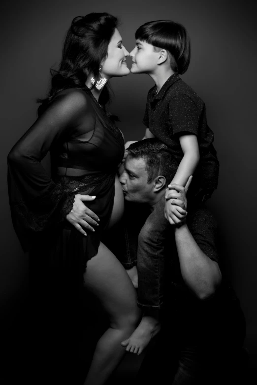 a black and white photo of a man kissing a woman, a black and white photo, reddit, conceptual art, portrait of family of three, studio!! portrait lighting, pregnancy, luke evans