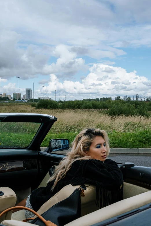 a woman sitting in the driver's seat of a convertible car, inspired by Elsa Bleda, ava max, over the horizon, overlooking, miro petrov